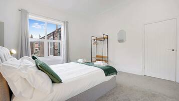 A bedroom with a bed, a window, a wardrobe, and a door.