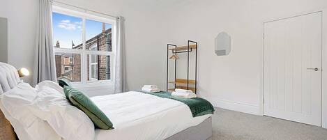 A bedroom with a bed, a window, a wardrobe, and a door.