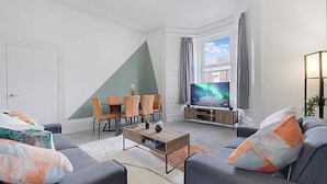 Una sala de estar moderna con comedor, televisor y vista al cielo.