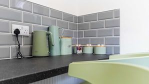 Una encimera de cocina con un enchufe, una tetera y una taza.