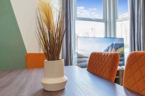 A table with a vase of dried plants, two chairs, and a window with a view of a mountain landscape. - Charming 5-Bed Home in Sunderland by Stay with Us (Tyne and Wear)