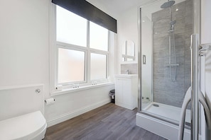 Ein modernes Badezimmer mit Toilette, einer Duschkabine und einem Fenster.