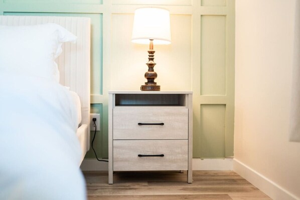 Un dormitorio con cama, una mesita de noche con lámpara y una cómoda.