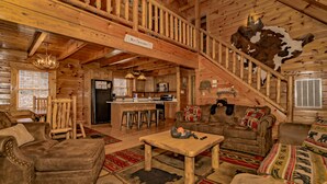 A cozy log cabin interior with a kitchen, dining area, and a staircase. - Scenic Hideaway: Pet-Friendly, Secluded, Game Room, fire pit, hot tub, Wi-Fi (Sevierville)