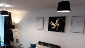 Ein modernes Wohnzimmer mit einem schwarzen Sofa, blaustichigen Kissen und Kunstwerken an der Wand.