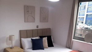 Ein Hotelzimmer mit einem großen Bett, einem Nachttisch, einer Lampe und Bildern an der Wand.
