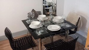 Ein Essbereich mit einem Tisch, gedeckt für vier Personen, umgeben von schwarzen Stühlen mit Metallbeinen.