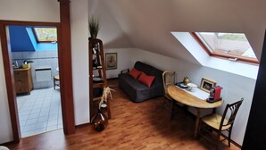 A cozy loft apartment with a dining area, a sofa, a coffee table, and a skylight. - Studio Spacieux, Route des Vins (Rosheim)