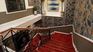 A staircase with a red carpet, a metal railing, and a wall with geometric patterns. - AURES HOTEL BY ATLANTIS (Akbou)