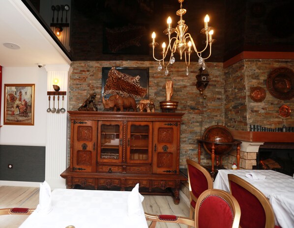 A hotel room with a wooden cabinet, a chandelier, a painting, and a fireplace.