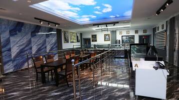 A modern restaurant with a high ceiling, marble flooring, and a view of the sky through a skylight.