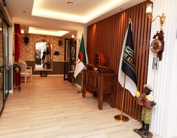 Un pasillo con suelo de madera, un escritorio de madera con una bandera, un perchero y un reloj de pared.