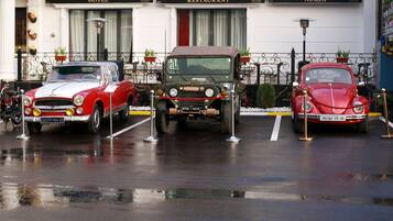 Three vintage cars parked in front of a building with signs for a hotel, restaurant, and a bar.