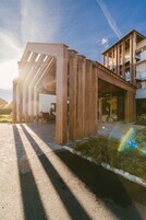Un edificio moderno con fachada de madera y una zona de estar exterior cubierta.