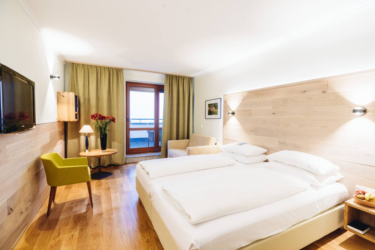 Een hotelkamer met een bed, een bureau, een stoel, een lamp en uitzicht op de omgeving.
