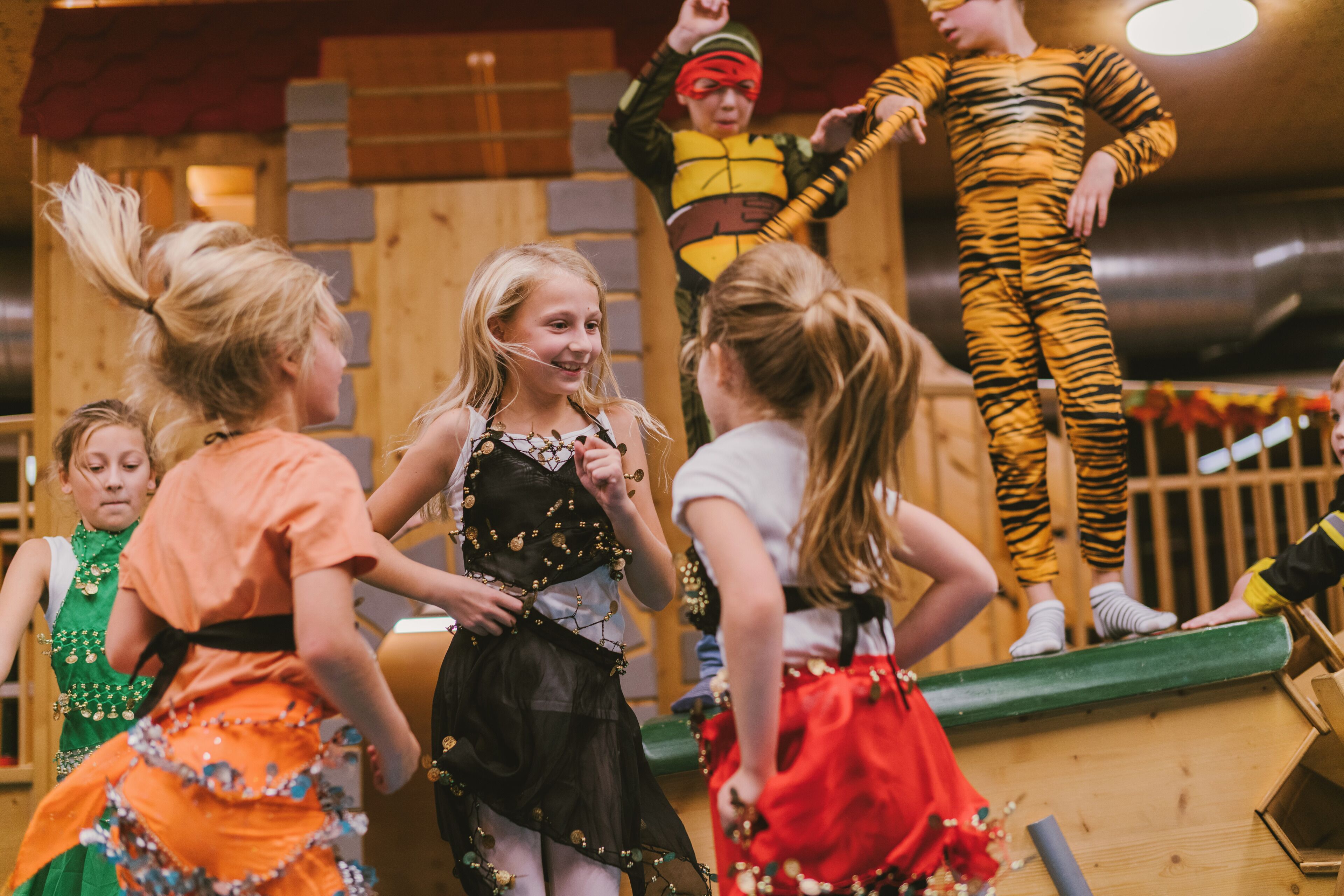 Eine Gruppe von Kindern in Kostümen auf einer Bühne mit einer Holzdecke.