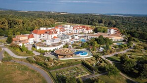 An aerial view of a resort with multiple buildings, a swimming pool, and landscaped gardens. - Reiters Finest Family 4s (Bad Tatzmannsdorf)