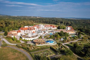 Vista aérea de un complejo turístico con varias construcciones, una piscina y jardines ajardinados.