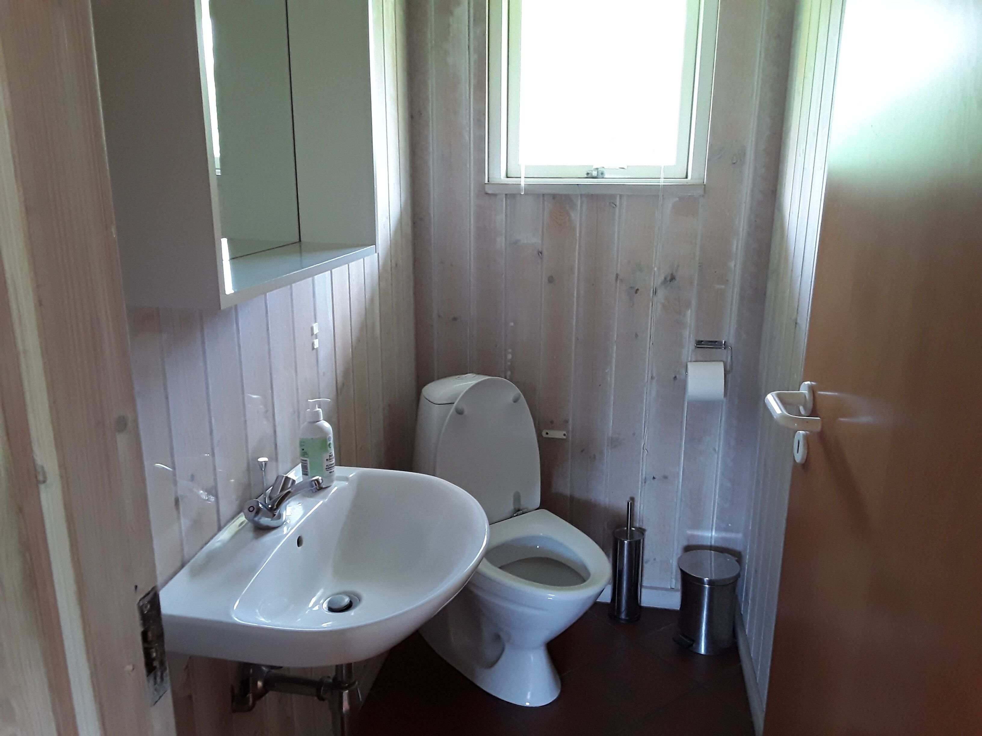 Ein kleines Badezimmer mit Waschbecken, Toilette und einem kleinen Mülleimer.