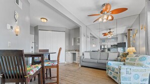 A spacious living area with a dining table, wooden chairs, a grey sofa, and patterned armchairs. - ⭐Adorable Bay Side Condo - Lei Lani Village 112⭐ (Orange Beach)