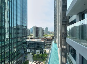 Un moderno edificio de gran altura con fachada de vidrio, piscina en la azotea y edificios altos circundantes.