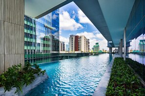 Ein moderner, überdachter Swimmingpool mit Glaswänden und Blick auf die umliegenden Gebäude.