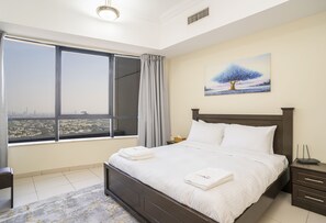 Habitación de hotel con una cama grande, una mesita de noche, una lámpara y un cuadro de un árbol en la pared.