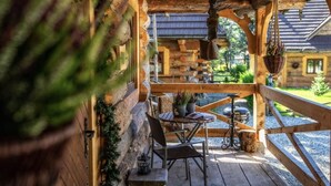 A wooden deck with a table and chairs, surrounded by a rustic cabin. - Mountain Shelter by Loft Affair (Zakopane)
