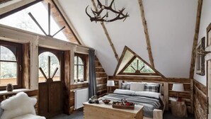 A cozy log cabin bedroom with a loft bed, a wooden chest, and a rustic chandelier. - Mountain Shelter by Loft Affair (Zakopane)