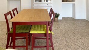 A dining area with a wooden table and red chairs, a white cabinet with glass doors, and a small window with shutters. - La Casedda Verde - Pisticci - nature and relaxation (Basilicata)