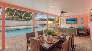 Un área de piscina interior con una mesa de comedor para cuatro personas, rodeada de sillas de mimbre.