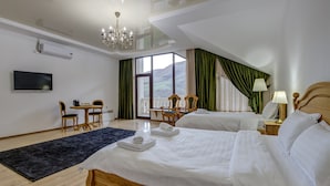 A hotel room with two beds, a desk with chairs, a TV, and a view of the outdoors. - Mountain View Hot Spring Resort (Koy-Tash)