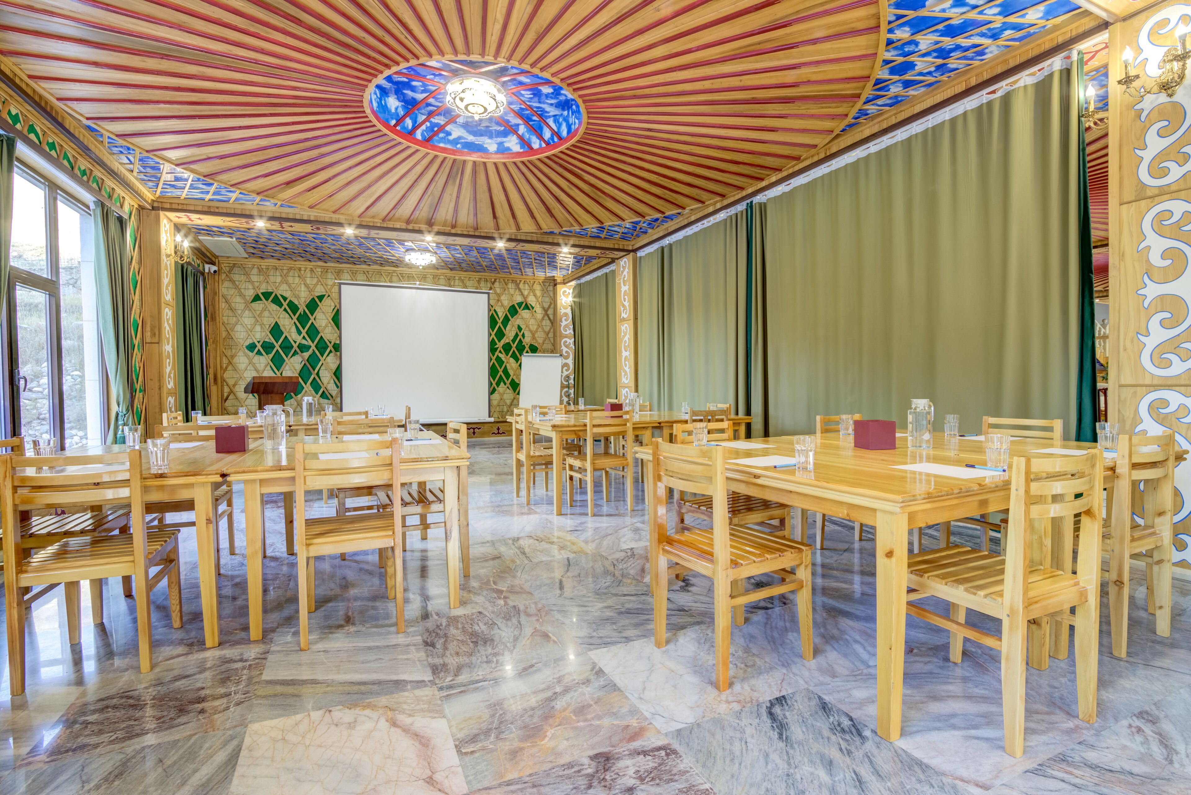 A conference room with wooden tables and chairs, a whiteboard, and a decorative ceiling.