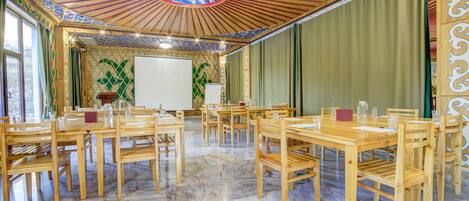 A conference room with wooden tables and chairs, a whiteboard, and a decorative ceiling.
