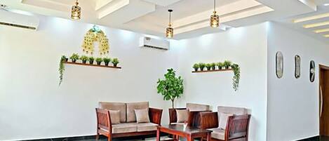 Un vestíbulo moderno con un conjunto de sofás, plantas colgantes e iluminación colgante.