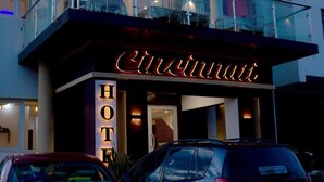 L'ingresso di un hotel con un neon che riporta la scritta "Cincinnati Hotel" e una scala che conduce a un balcone superiore.