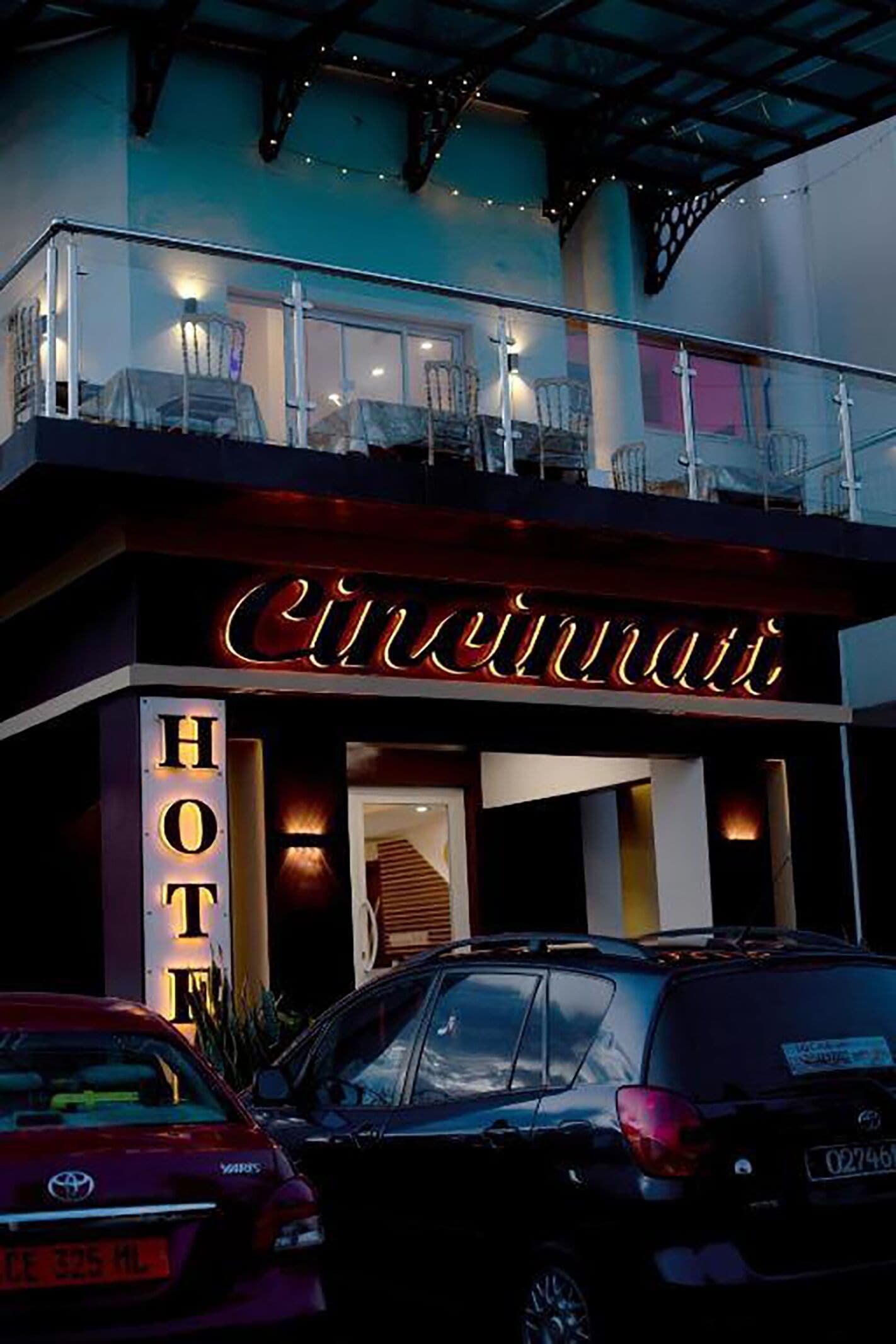 A hotel with a balcony and a neon sign.
