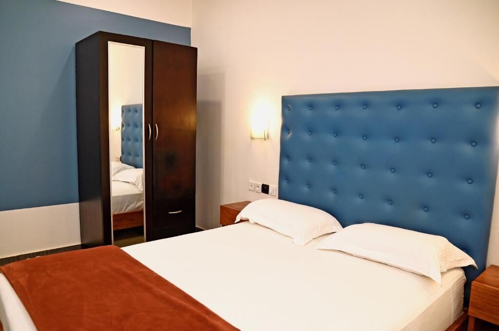 A hotel room with a bed, a wardrobe, and a nightstand.