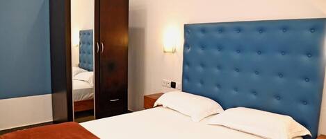 A hotel room with a bed, a wardrobe, and a nightstand.