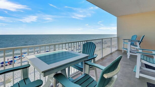 A balcony with a view of the beach and ocean.