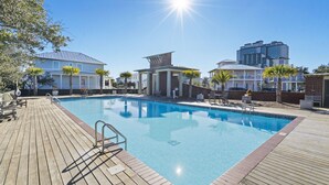 Ein Schwimmbecken mit Holzterrasse, umgeben von Gebäuden und Palmen.
