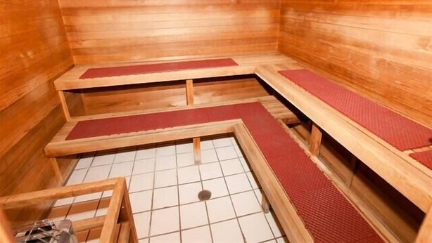 Un sauna avec des bancs en bois et des tapis rouges.