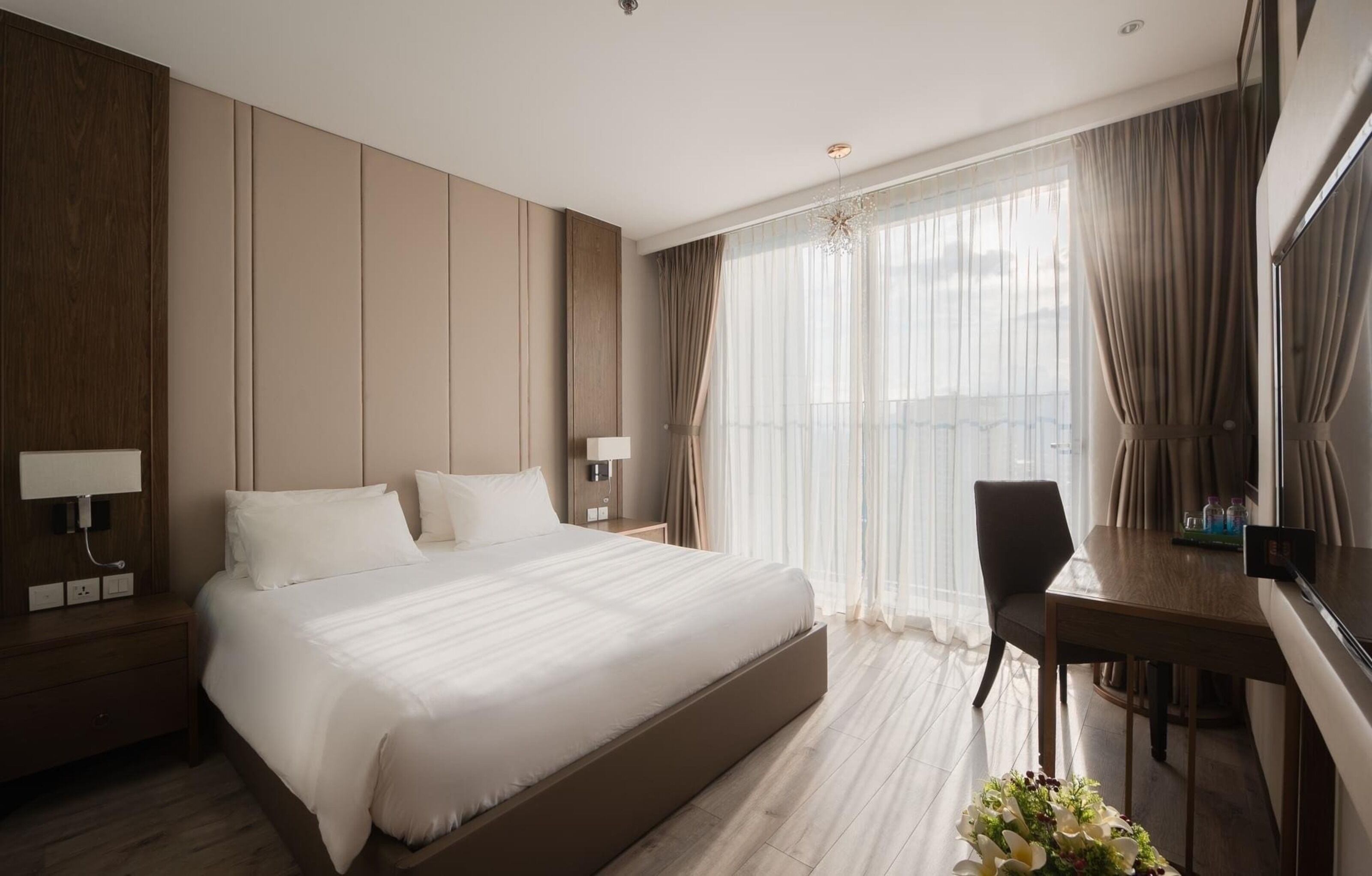 A modern hotel room with a large bed, a desk, and a chair.