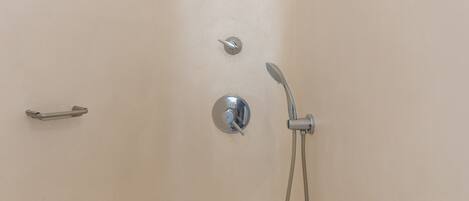 A shower with a handheld showerhead and a wall-mounted control panel.
