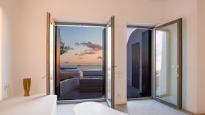 Un dormitorio con un balcón y una ventana grande, una cama y una mesita de noche.