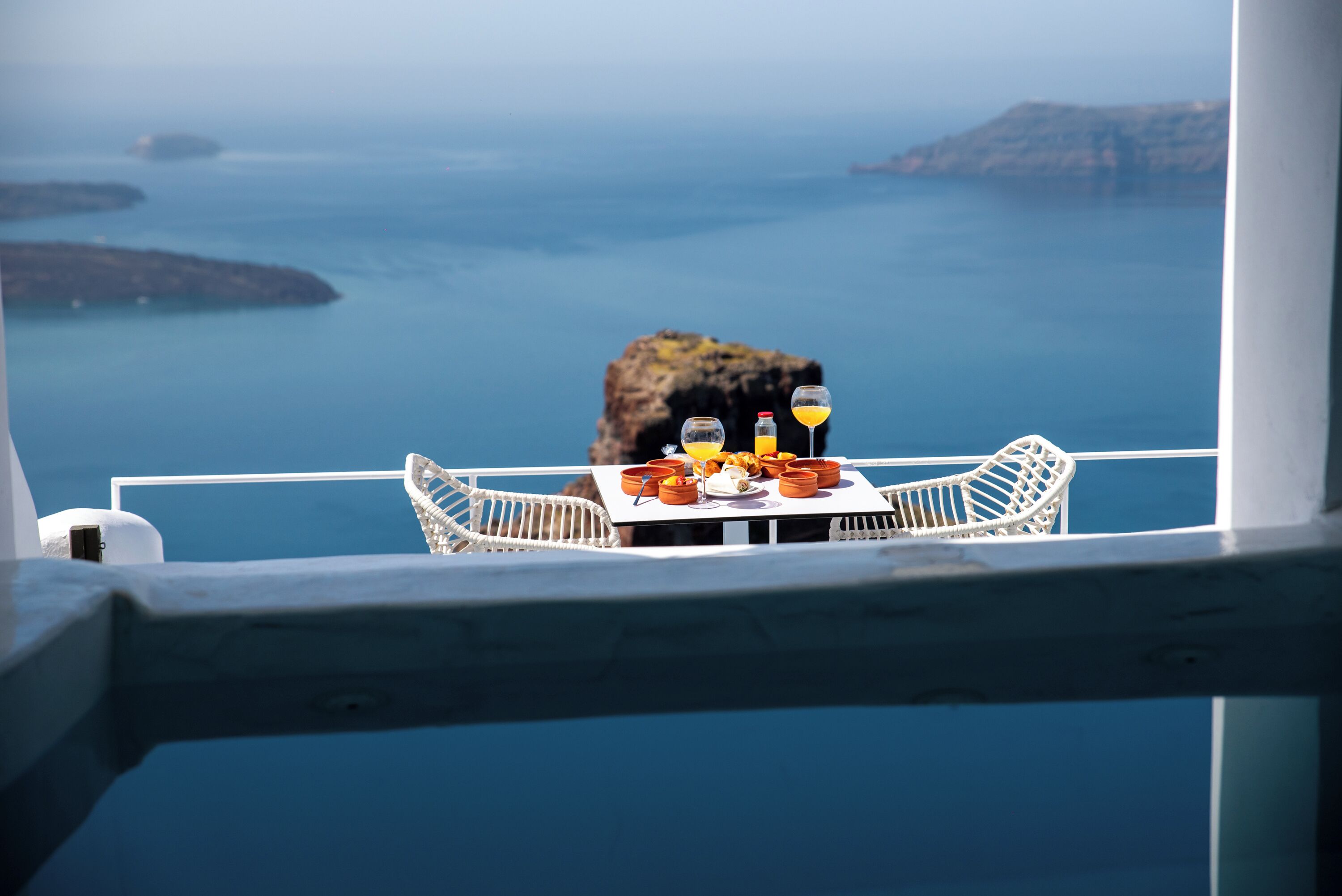 A table with food and drinks on a balcony overlooking the sea.