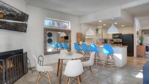 A modern kitchen with white cabinets, a central island, and blue chairs around a round table. - Grand Mountain Getaway | Ski, Fireplace, EV Charger (Durango)