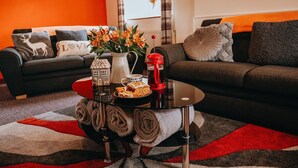 Una sala de estar con un sofá, una mesa de centro con un florero y una bandeja con galletas.