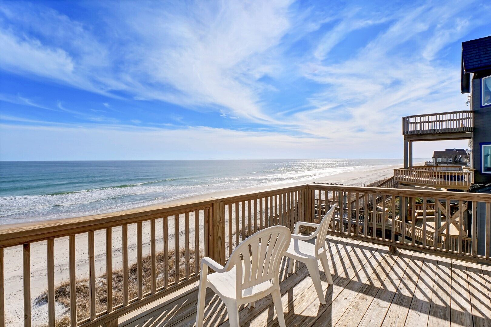 Une terrasse en bois offrant une vue sur la plage et l’océan.