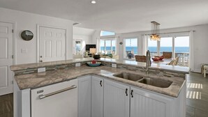 A kitchen with a large island, white cabinetry, and a view of the ocean.